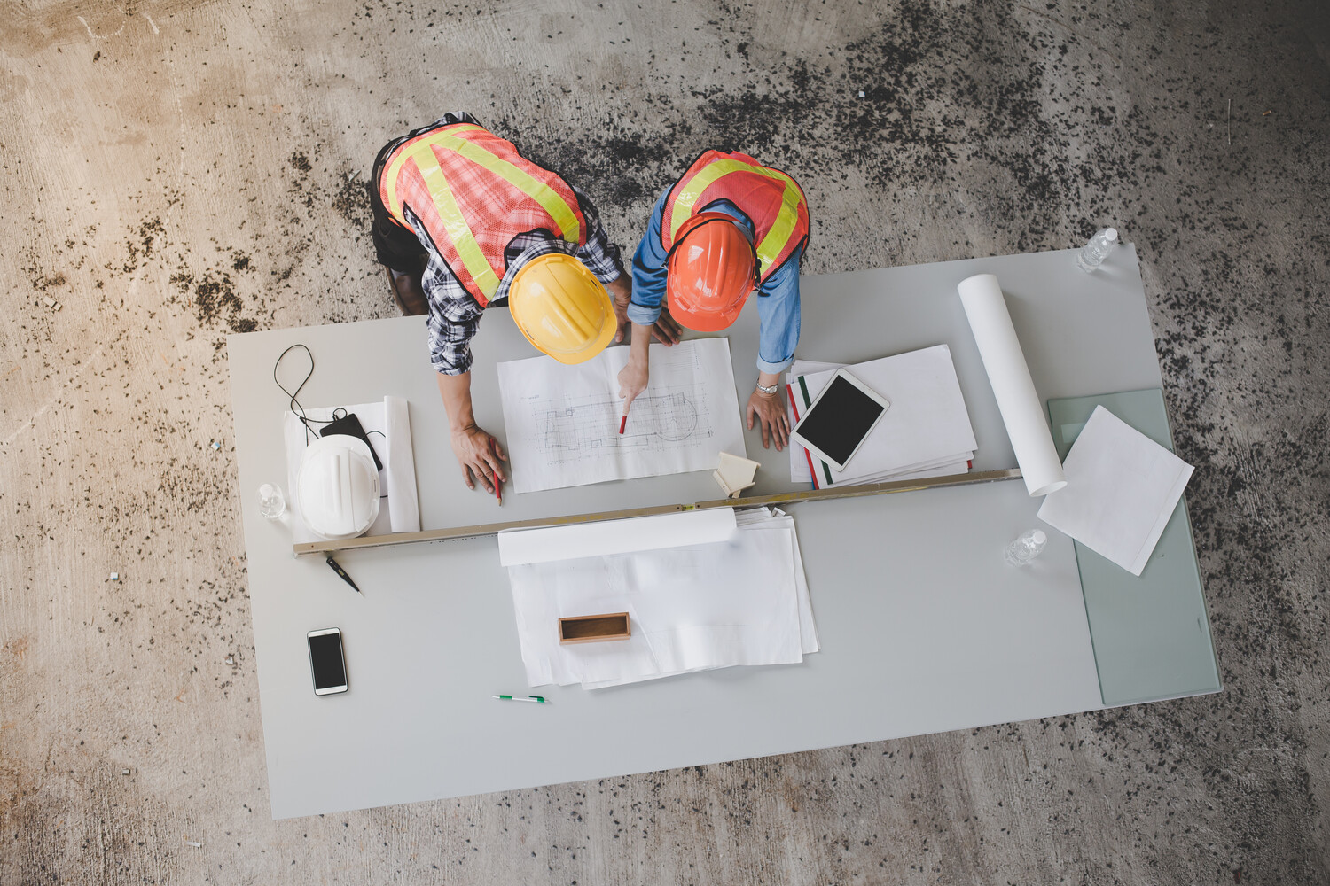 Two commercial remodel contractors reviewing architectural plans, representing tailored renovation solutions for business spaces.