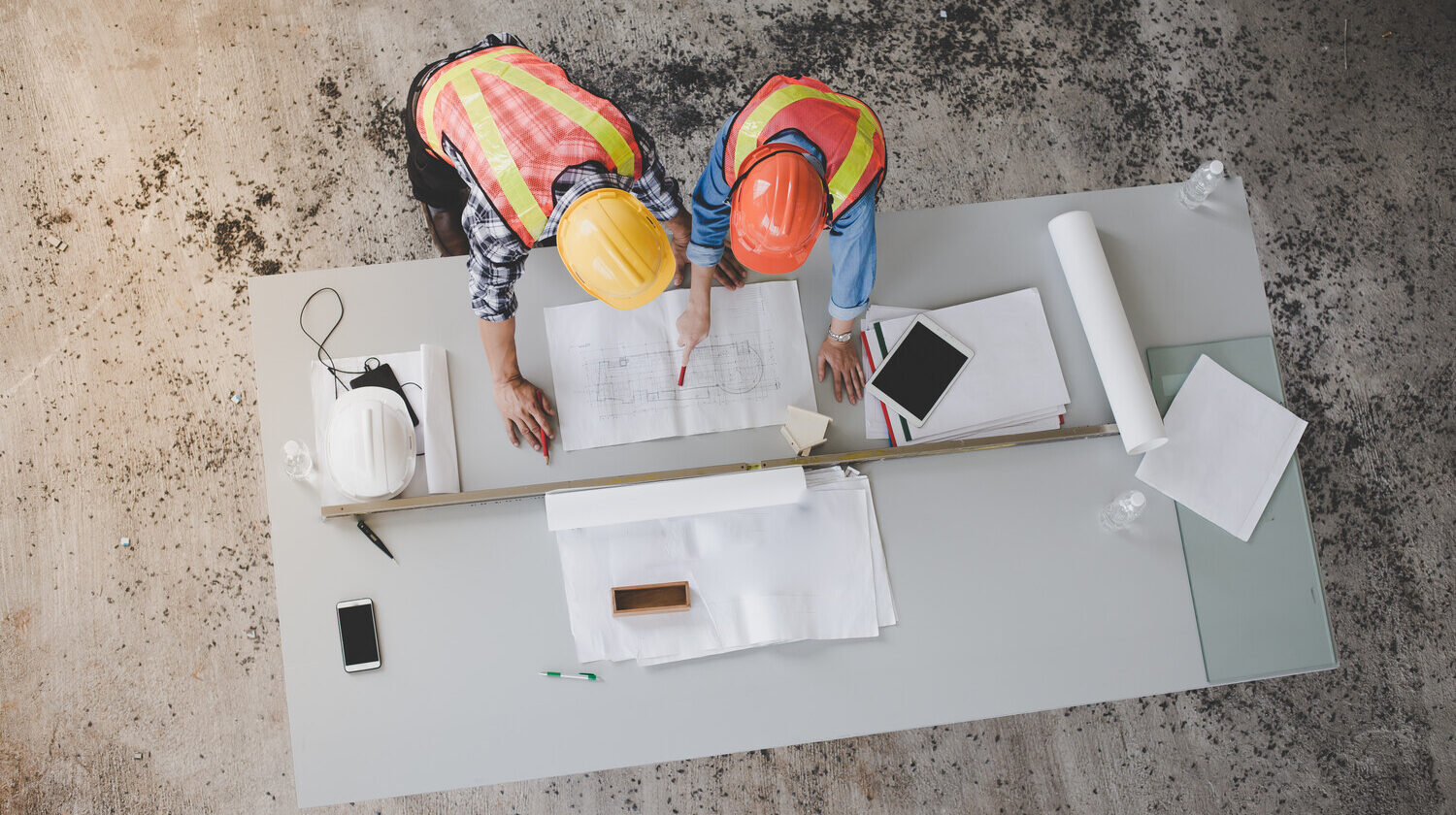 Construction management company team reviewing blueprints on a table, ensuring comprehensive project oversight and detailed planning.